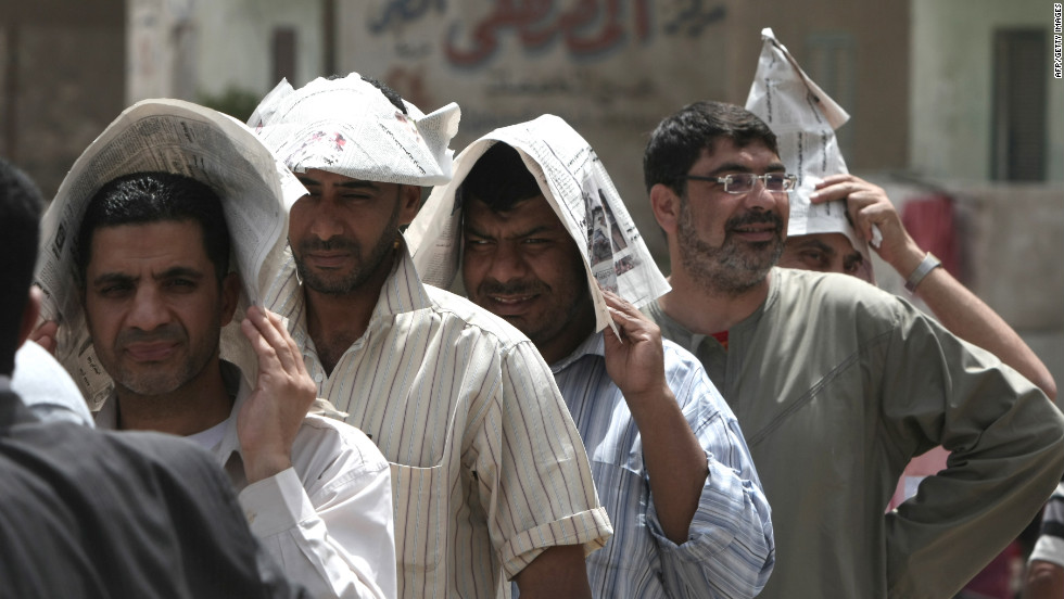 Egyptian men shield themselves from the hot sun outside a Cairo polling station Wednesday.