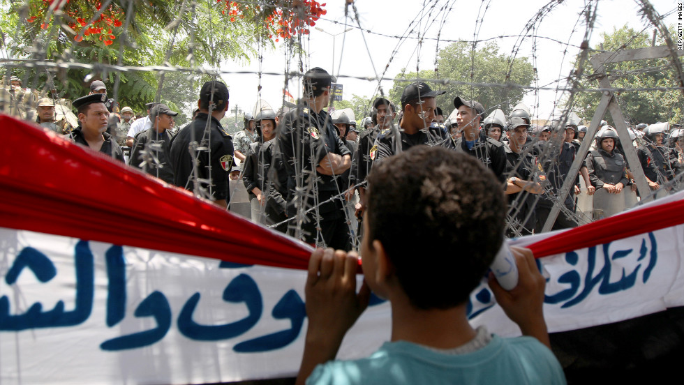 A boy peers through barbed wire at Egyptian military police standing guard outside the Constitutional Court in Cairo on Thursday, June 14.