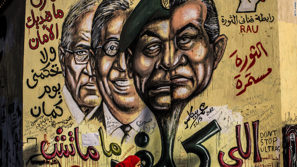 People walk past graffiti showing faces of ousted Egyptian president Hosni Mubarak, right; Field Marshal Hussein Tantawi, second right; former Secretary General of the Arab League Amr Mussa, second left, and former prime minister and presidential candidate Ahmed Shafiq, left, at Tahrir square.  