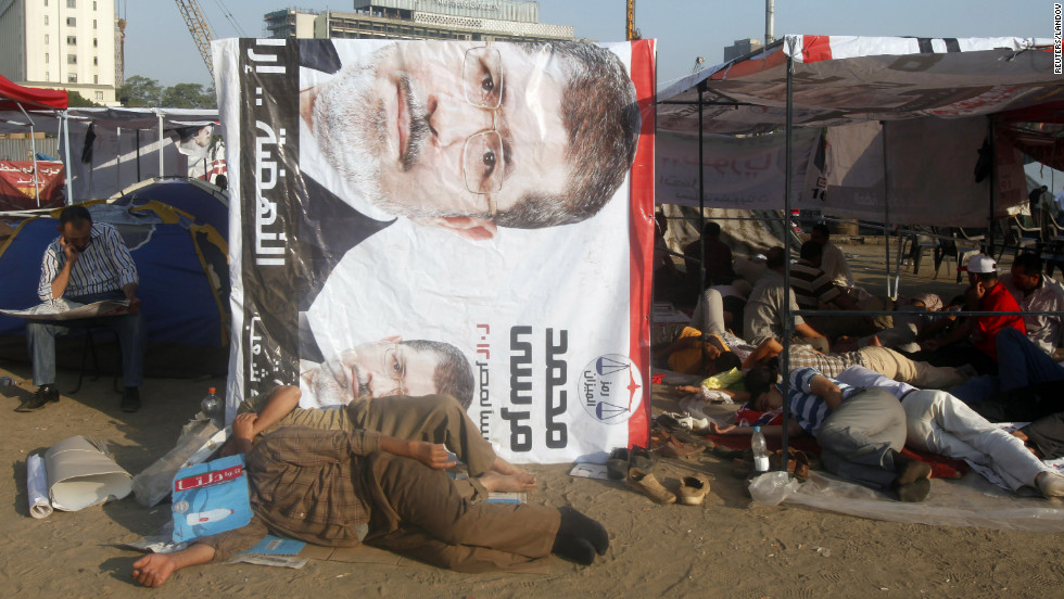 Egyptian activists rest at the foot of a banner of presidential candidate Mohamed Morsi in Cairo&#39;s Tahrir Square on Thursday, June 21. 