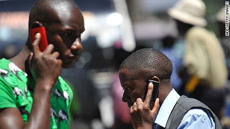 People walk while speaking on the phone on October 1,2012 in Nairobi, as Kenya confirmed a switch-off of counterfeit mobiles will take place at the end of the month.The mobile networks will be forbidden from activating new &#39;fake&#39; devices bought after October 1. Government officials said the move was designed to protect consumers from hazardous materials and to safeguard mobile payment systems and prevention of crime. The government said three million users were using counterfeit handsets as of June. AFP PHOTO / SIMON MAINA (Photo credit should read SIMON MAINA/AFP/GettyImages) 