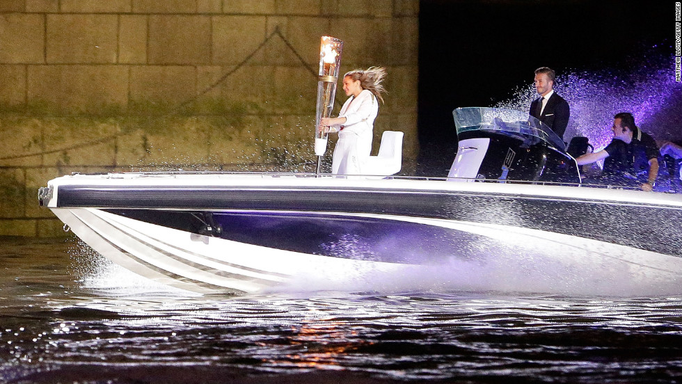 Beckham passes under London&#39;s Tower Bridge in a speedboat carrying the Olympic Torch in 2012.