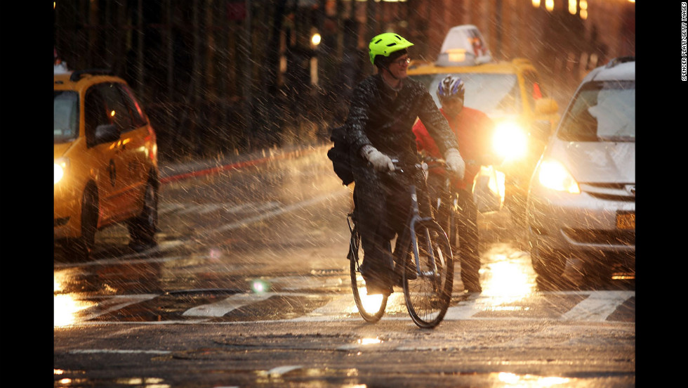 Bicyclists wait at a light in wind, snow and sleet on Friday.