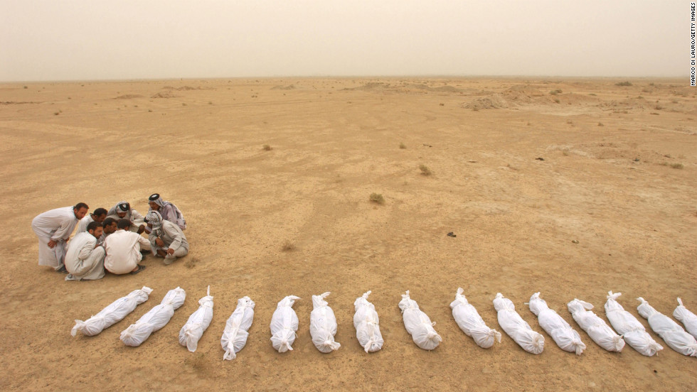 Iraqi men check a list near the remains of bodies excavated from a mass grave on the outskirts of Al Musayyib on May 31, 2003. Locals said they uncovered the remains of hundreds of Shiite Muslims allegedly executed by Saddam Hussein&#39;s regime after their uprising following the 1991 Gulf War.