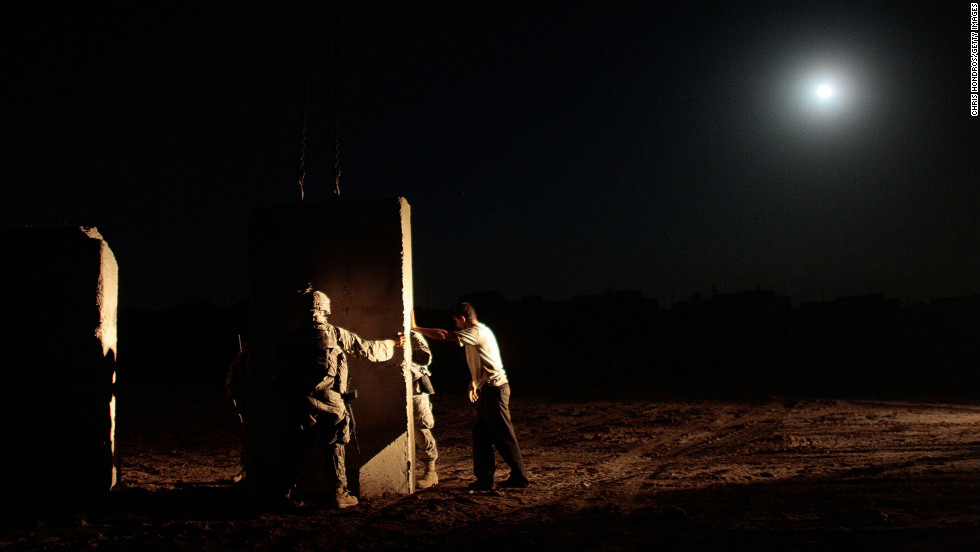U.S. soldiers and an Iraqi contractor build a concrete wall between Sunni and Shiite areas of the south Dora neighborhood of Bagdhad in the early hours of July 4, 2007.