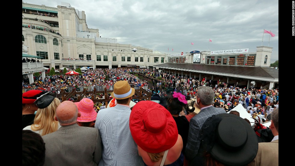 Race fans in festive hats look over the paddock.
