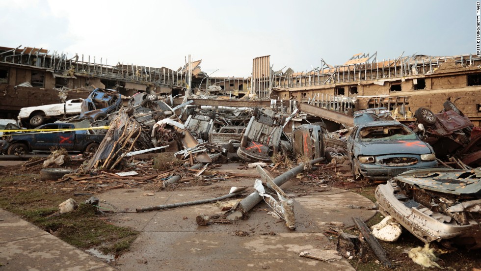 Cars marked with an orange X, meaning they have been checked for occupants, are piled up in front of the entrance to the damaged Moore Medical Center on May 20.