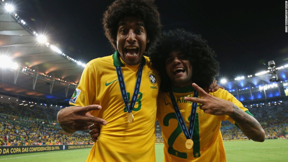 Brazil players Dante, left, and Dani Alves, in a wig, celebrate with their winner&#39;s medals.