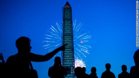 People watch fireworks burst behind the Washington Monument on the National Mall July 4, 2013 in Washington, DC. 