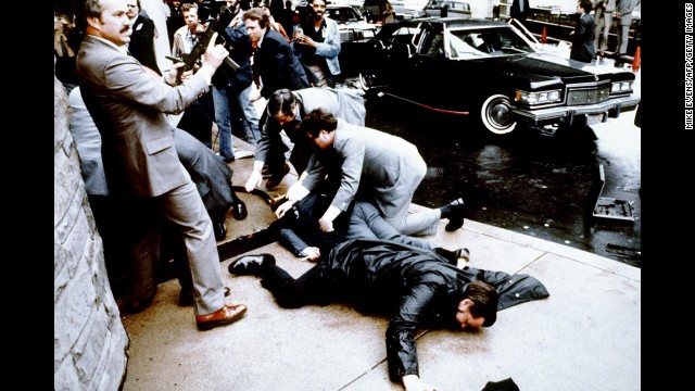 This photo taken by presidential photographer Mike Evens on March 30, 1981 shows police and Secret Service agents reacting during the assassination attempt on then US president Ronald Reagan, after a conference outside the Hilton Hotel in Washington, D.C.. Police officer Thomas Delahanty (foreground) and Press Secretary James Brady (behind) lay wounded on the ground. Reagan was hit by one of six shots fired by John Hinckley, who also seriously injured press secretary James Brady (just behind the car).  Reagan was hit in the chest and was hospitalized for 12 days. Hinckley was aquitted 21 June 1982 after a jury found him mentally unstable. (Photo credit should read MIKE EVENS/AFP/Getty Images)