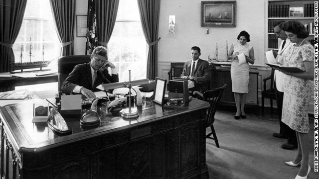 Thomas, third right, takes notes as President John F. Kennedy speaks on the phone in the Oval Office, on August 23, 1962.