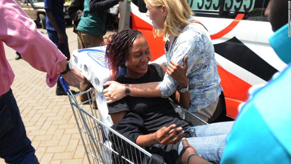 A woman is pulled by a shopping cart to an ambulance.