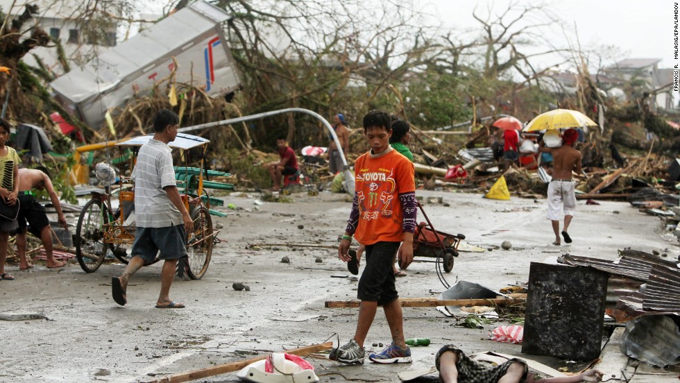 People walk past a victim left on the side of a road in Tacloban.