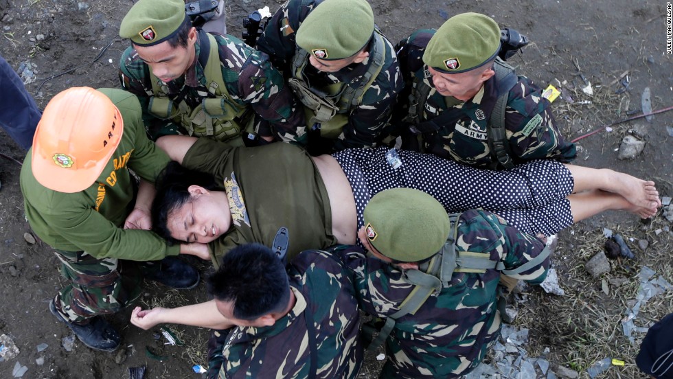 Soldiers help a woman after she collapsed November 13 while waiting in line to board a military plane at Tacloban&#39;s airport.