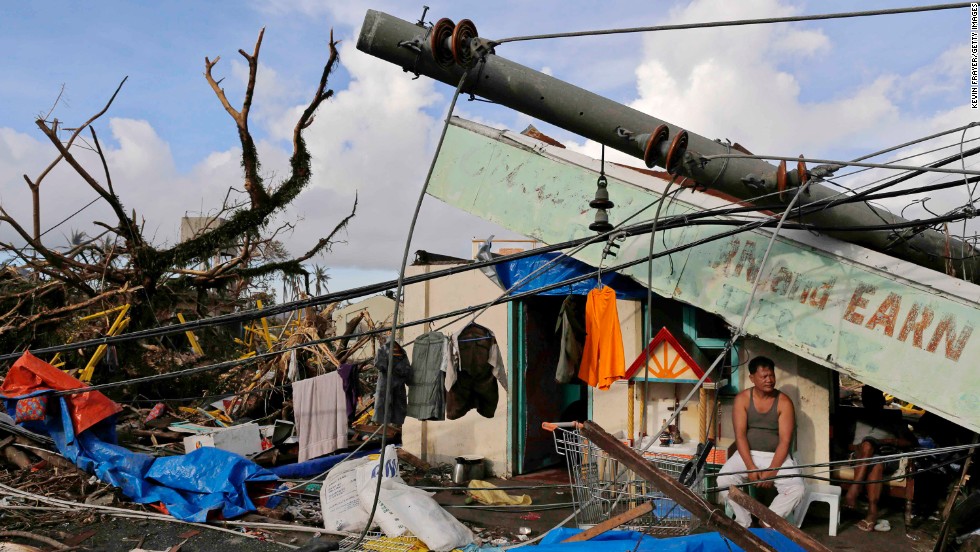 A man sits in front of his destroyed business November 13 in Tacloban.