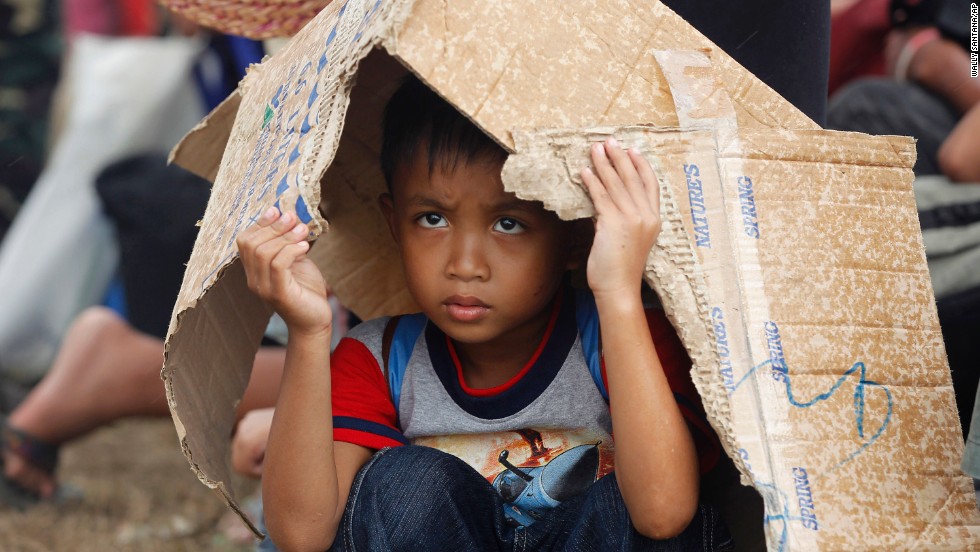 A boy takes cover from rain while waiting for an evacuation flight from Tacloban&#39;s airport November 14.