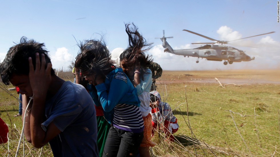 Trapped residents protect themselves from dust as a U.S. Navy helicopter takes off Saturday, November 16, on the Philippines&#39; Manicani Island.
