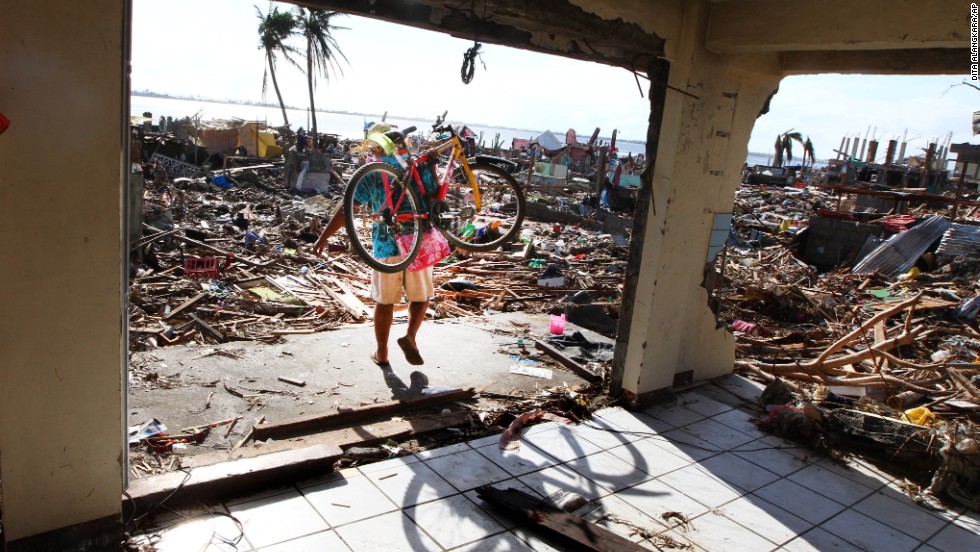 A man carries a bicycle as he walks through the ruins of a Tacloban building November 16.