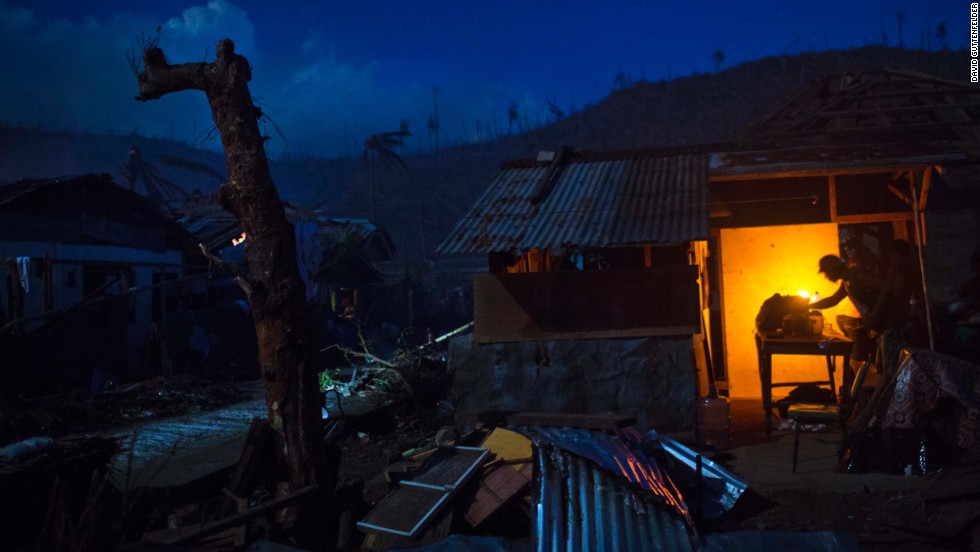 A survivor cooks dinner in front of his damaged home in Marabut, Philippines, on Friday, November 15.