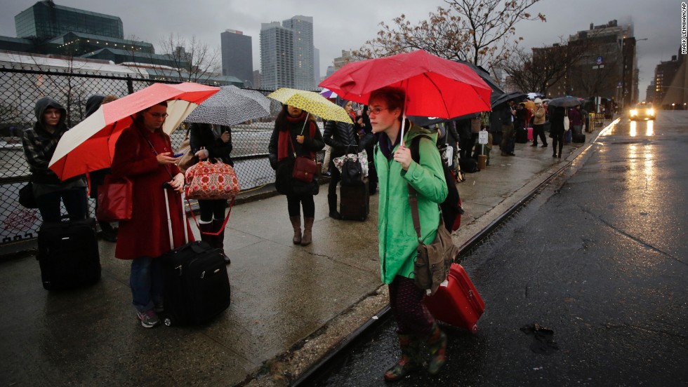 Passengers wait for a BoltBus to arrive during a light rain on Wednesday, November 27, in New York. A wall of storms packing ice, sleet and rain threatened to suspend holiday travel plans as millions of Americans took to the roads, skies and rails.