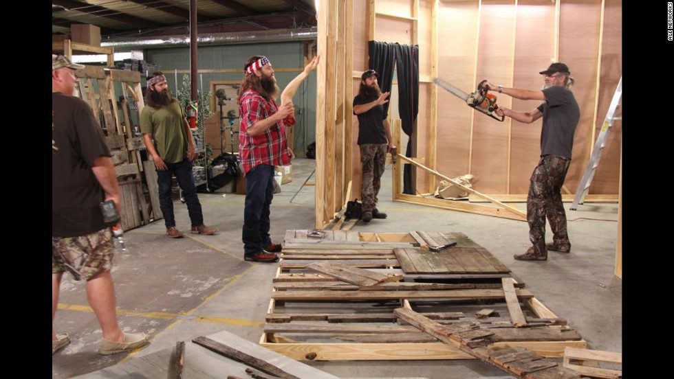 The Duck Commander crew works on transforming their warehouse into a &quot;scarehouse&quot; during a Halloween episode. Holding the chainsaw is Si Robertson, who founded the company along with his brother Phil, not pictured. 