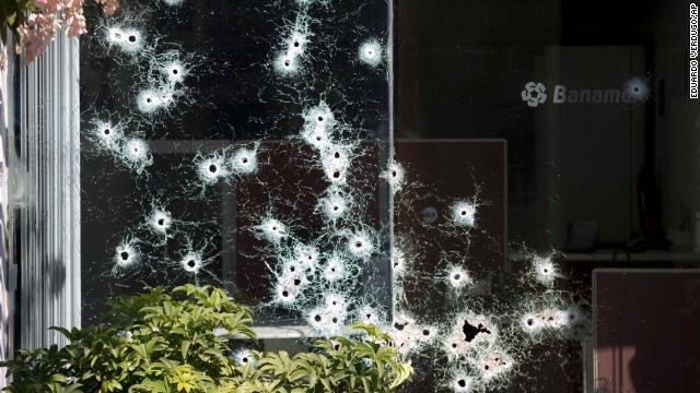 The window of a bank is riddled with bullet holes in the town of Apatzingan, Michoacan state, Mexico, Saturday, Jan. 11, 2014. Residents from various towns in western Michoacan are protesting the arrival of vigilantes, or members of "self-defense" groups, to their communities by destroying property. Vigilante groups have formed to confront drug cartels in parts of Michoacan. (AP Photo/Eduardo Verdugo)