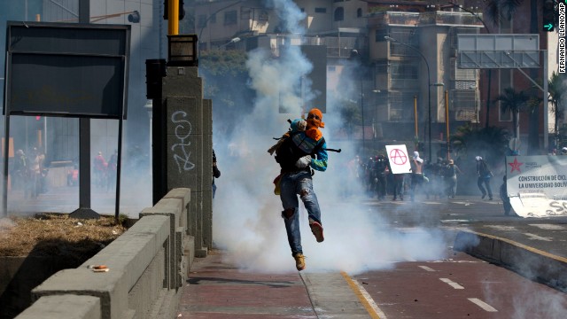 A masked anti-government demonstrator returns a teargas canister to Bolivarian National Guards during clashes in Caracas, Venezuela, Saturday, April 12.