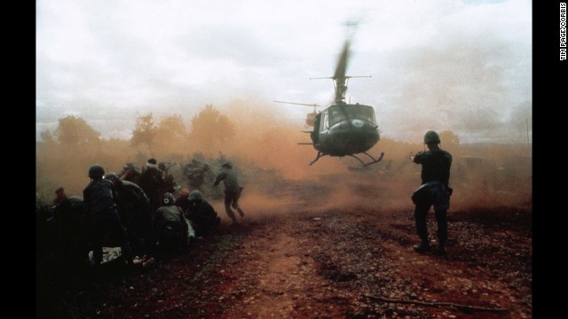 1965, Vietnam --- A US helicopter takes off from a clearing near Du Co SF camp, Vietnam. Wounded soldiers crouch down in the dust of the departing helicopter. The military convoy was on its way to relieve the camp when it was ambushed. | Location: near Du Co SF camp, Vietnam. --- Image by © Tim Page/CORBIS