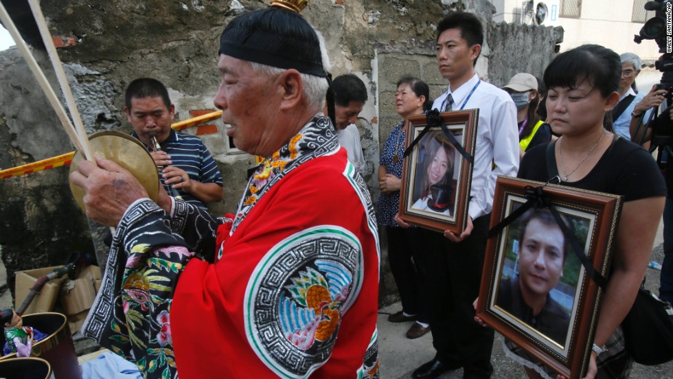Relatives of victims pray with the victims' portraits during a makeshift ceremony at the crash site on the outlying island of Penghu, Taiwan, on July 24. Stormy weather on the trailing edge of Typhoon Matmo was the likely cause of the plane crash, the airline said Thursday.