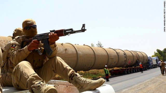 A section of an oil refinery is guarded as it is brought on a lorry to the Kawergosk Refinery, some 20 kilometres east of Arbil, the capital of the autonomous Kurdish region of northern Iraq, on July 14, 2014. The International Energy Agency (IEA) said on July 11, that an offensive by jihadists in northern Iraq had cut output by 260,000 barrels a day in June to 3.17 million, after fighting forced the closure of the country&#39;s biggest refinery and slashed production from the giant Kirkuk field