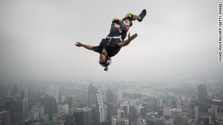 A BASE jumper leaps from the 300-meter (approximately 984-foot) Open Deck of Malaysia&#39;s landmark Kuala Lumpur Tower. BASE is an acronym for building, antenna, span, earth -- referring to the types of fixed objects participants leap from before using parachutes to slow their falls.