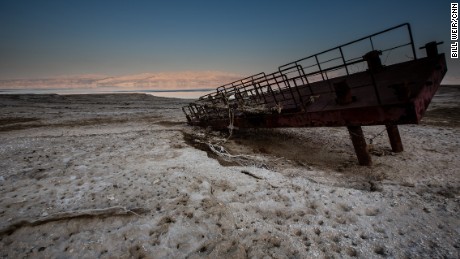 A rusty old dock lying atop a desert encrusted in salt. What used to be the shoreline of the Dead Sea now lies hundreds of feet from the waters edge.