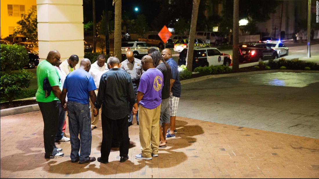 People pray in a hotel parking lot across the street from the scene of the shooting on June 17. Every Wednesday evening, the church holds a Bible study in its basement.