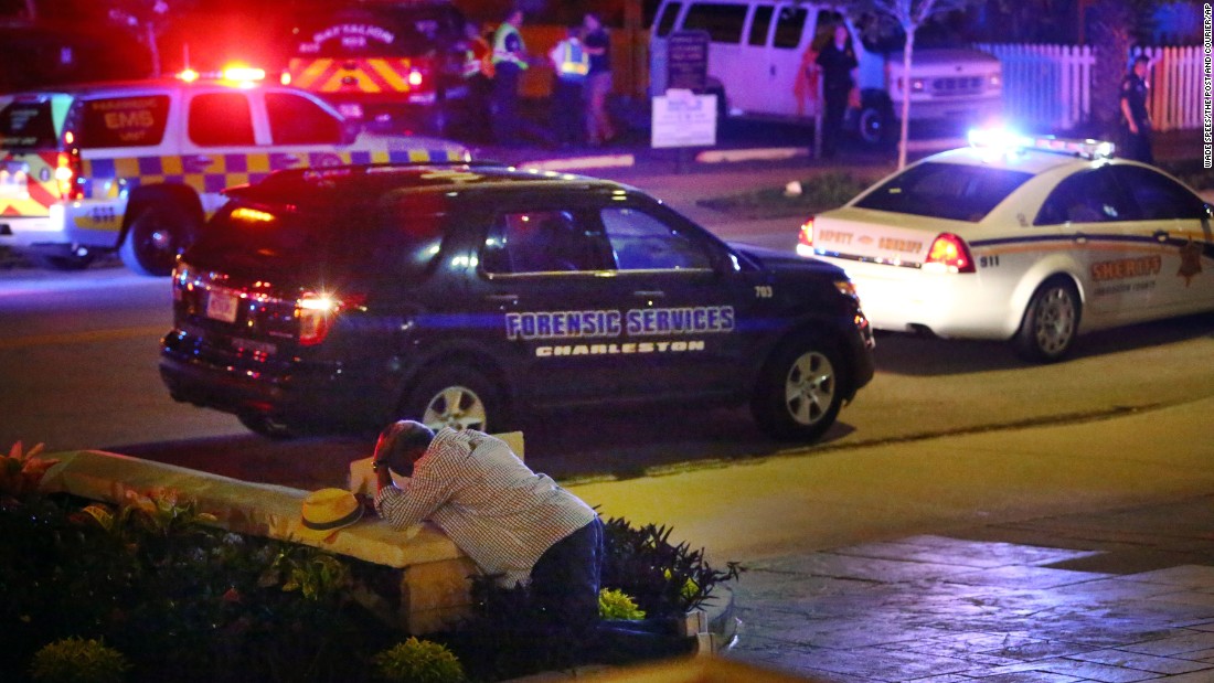 A man kneels across the street from where police gathered outside the church on June 17.