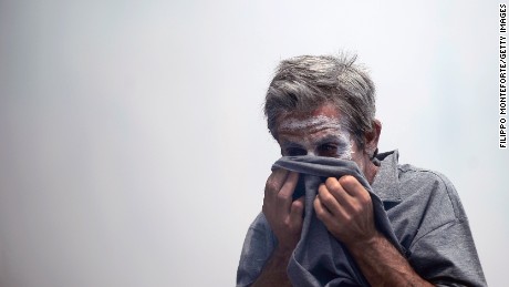 A demonstrator protects his face from teargas thrown by riot police in front of the Greek parliament on June 29, 2011 during a 48-hour general strike protest against the bankruptcy-threatened government which is desperately trying to push through sweeping austerity cuts. Amid angry street protests, MPs approved 28.4 billion euros ($40.7 billion) in spending cuts, unlocking a 12-billion-euro payout from the European Union and the International Monetary Fund.