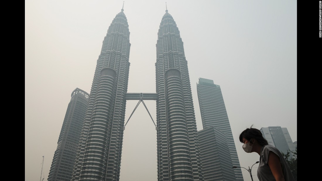 A woman wears a mask as haze shrouds the Petronas Twin Towers in Kuala Lumpur, Malaysia, on Friday, September 11.
