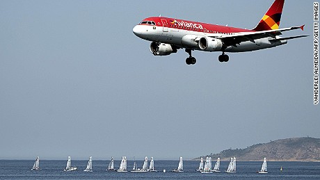 In the forefround  an Avianca airliner lands in the Santos Dumont airport (not framed) as sailing boats compete in the International Sailing Regatta held in the Guanabara Bay in Rio de Janeiro, Brazil on August 19, 2015, an event that serves as a test for the Rio 2016 Olympic Games.    AFP PHOTO/VANDERLEI ALMEIDA        (Photo credit should read VANDERLEI ALMEIDA/AFP/Getty Images)