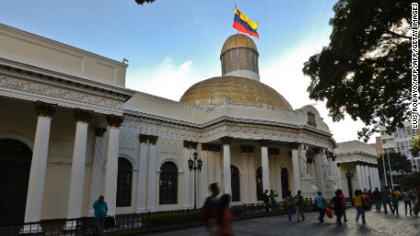 People walk past the National Assembly building in Caracas, on December 7, 2015. Venezuela's jubilant opposition vowed Monday to drag the oil-rich country out of its economic crisis and free political prisoners after winning control of congress from socialist President Nicolas Maduro. AFP  PHOTO/Luis Robayo / AFP / LUIS ROBAYO        (Photo credit should read LUIS ROBAYO/AFP/Getty Images)