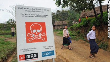 Students walk past a poster warning of a mine clearance operation by clearance team at a secondary school in the northern Laotian province of Xiangkhoang. During the Vietnam War, Laos became the world&#39;s most heavily bombed country per head of population.