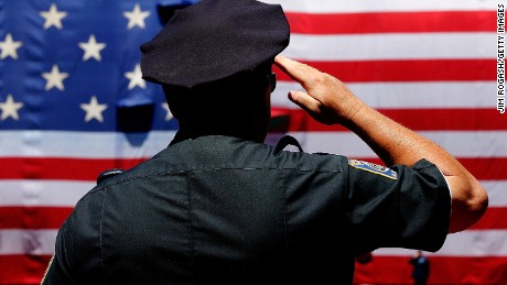 BOSTON, MA - JULY 5: A police officer salutes during the National Anthem before the first game of a doubleheader between the Baltimore Orioles and the Boston Red Sox at Fenway Park on July 5, 2014 in Boston, Massachusetts.  (Photo by Jim Rogash/Getty Images)