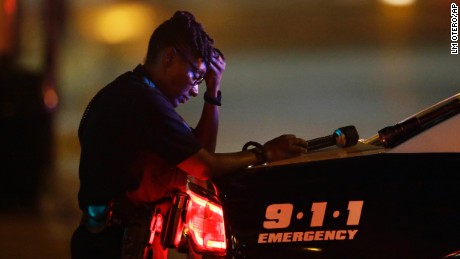 A Dallas police officer, who did not want to be identified, takes a moment as she guards an intersection in the early morning after a shooting in downtown Dallas, Friday, July 8, 2016. At least two snipers opened fire on police officers during protests in Dallas on Thursday night; some of the officers were killed, police said.