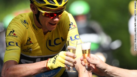 Chris Froome drinks a glass of champagne as he rides at the start of the 113 km twenty-first and last stage of the 103rd edition of the Tour de France.