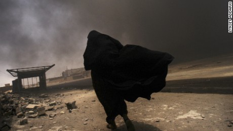 An Iraqi woman walks through a plume of smoke rising from a massive fire at a liquid gas factory as she searches for her husband in the vicinity of the fire in Basra, Iraq, May 26, 2003.  The fire was allegedly started by looters picking through the factory, and residents in the vicinity feared the explosion of the four liquid gas tanks on the premisis.   Weeks after the end of the war, looting continues to be one of the main problems for both Basra and Bagdad cities as coalition forces struggle to get life back to normal.
                                