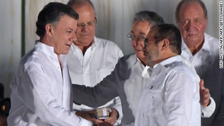 Cuban President Raul Castro greets Colombian President Juan Manuel Santos (L) and the leader of the FARC, Rodrigo Londono -- better known by his nom de guerre, Timoleon "Timochenko" Jimenez after the latter delivered a speech after signing the historic peace agreement between the Colombian government and the Revolutionary Armed Forces of Colombia (FARC), in Cartagena, Colombia, on September 26, 2016 
The Colombian government and the leftist FARC rebel force signed a historic peace accord to end a half-century conflict that has killed hundreds of thousands of people. Santos and "Timochenko" Jimenez, signed the deal at a ceremony in the Caribbean city of Cartagena, prompting loud cheers from the crowd which included numerous international dignitaries.
 / AFP / Luis ACOSTA        (Photo credit should read LUIS ACOSTA/AFP/Getty Images)