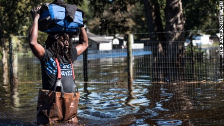 A man carries personal items through a flooded street caused by remnants of Hurricane Matthew on October 11, 2016 in Fair Bluff, North Carolina. Thousands of homes have been damaged in North Carolina as a result of the storm and many are still under threat of flooding. 