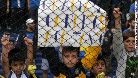 A boy holds placard with legends of gratitude to forward Carlos Tevez --referring to his impending transfer of  to the Chinese football-- during their Argentina First Division football match against Colon at La Bombonera stadium, in Buenos Aires, on December 18, 2016. / AFP / ALEJANDRO PAGNI        (Photo credit should read ALEJANDRO PAGNI/AFP/Getty Images)