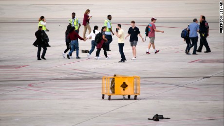 People are shown on the tarmac at Fort Lauderdale--Hollywood International Airport, Friday, January 6, in Fort Lauderdale, Florida. A gunman opened fire in the baggage claim area at the airport Friday, killing several people and wounding othersbefore being taken into custody in an attack that sent panicked passengers running out of the terminal and onto the tarmac, authorities said.