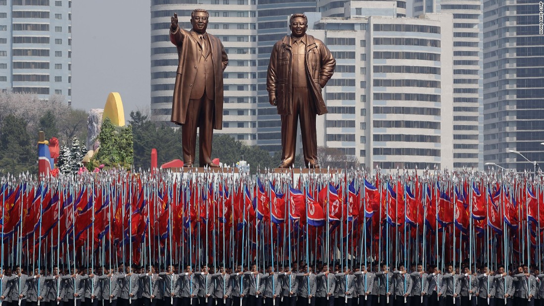 University students carry the national flag and two bronze statues of the late leaders Kim Il Sung and Kim Jong Il.