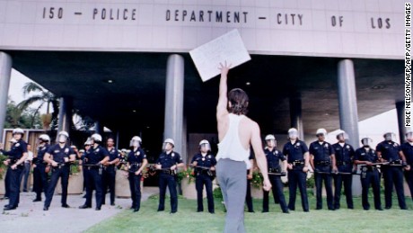 LOS ANGELES, CA - APRIL 30:  A demonstrator protesting the 29 April 1992 verdict in the trial of four Los Angeles police officers accused of beating motorist Rodney King holds a placard aloft before a line of police as protesters gathered at the Parker Center, the headquarters of the Los Angeles Police Department.  (Photo credit should read AFP PHOTO MIKE NELSON/AFP/Getty Images)