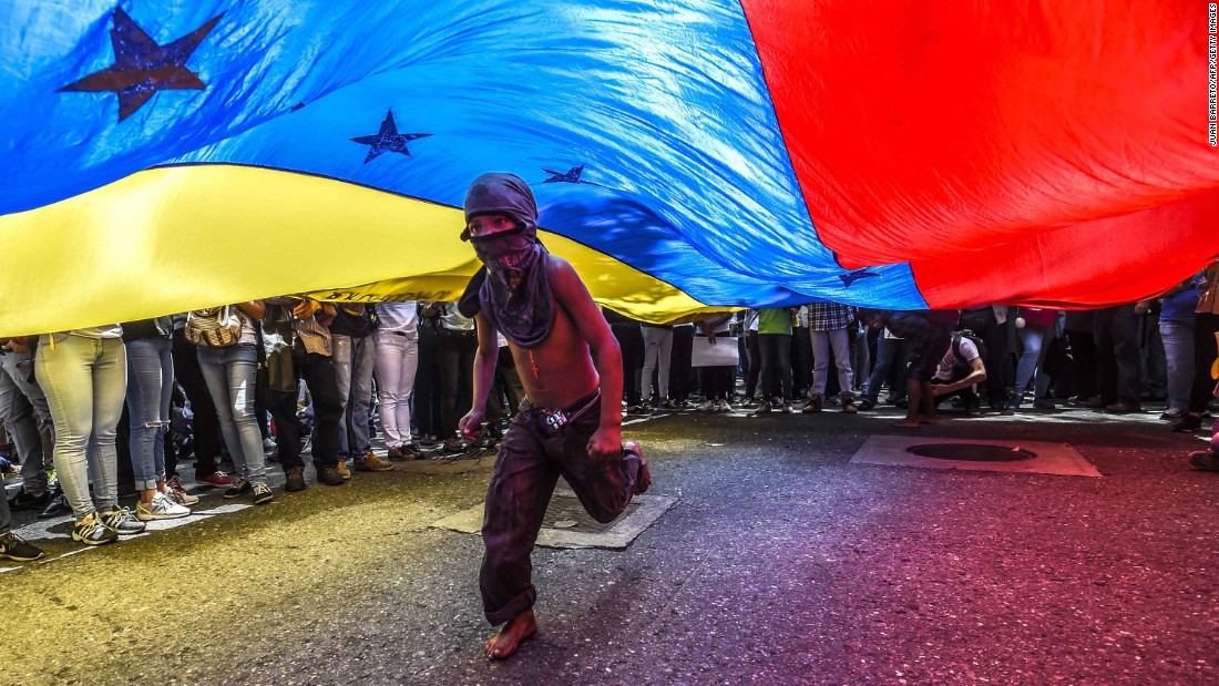 A boy runs under a national flag during a June 27 protest in Caracas.